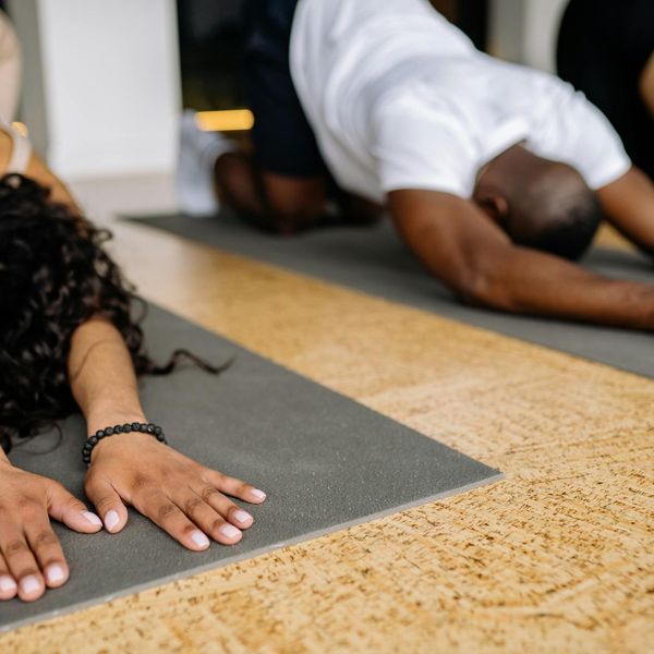 A diverse group of people practicing a stretching yoga pose in a studio.